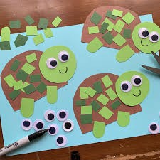A photograph of a paper turtle craft. The turtles are made out of paper cutouts, with googly eyes and square paper pieces glued onto their shells for decoration.